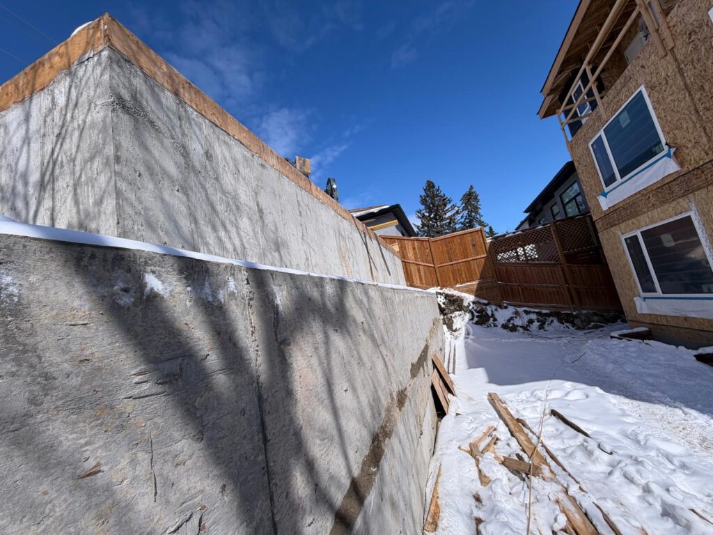 High-performance structural concrete retaining wall design for a Calgary residential property, ensuring building code compliance and foundation protection.